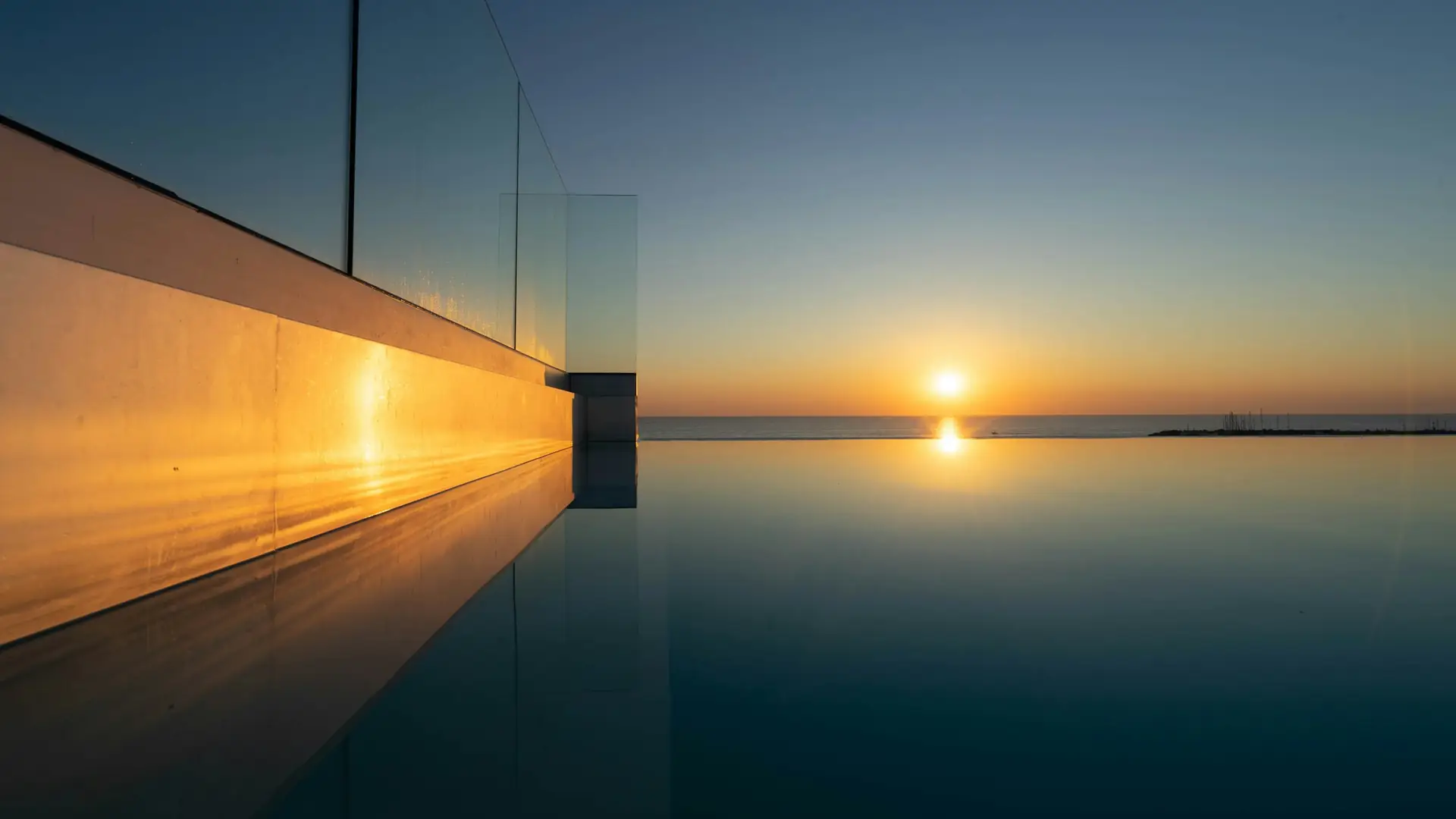 Borde de una piscina frente al mar al atardecer