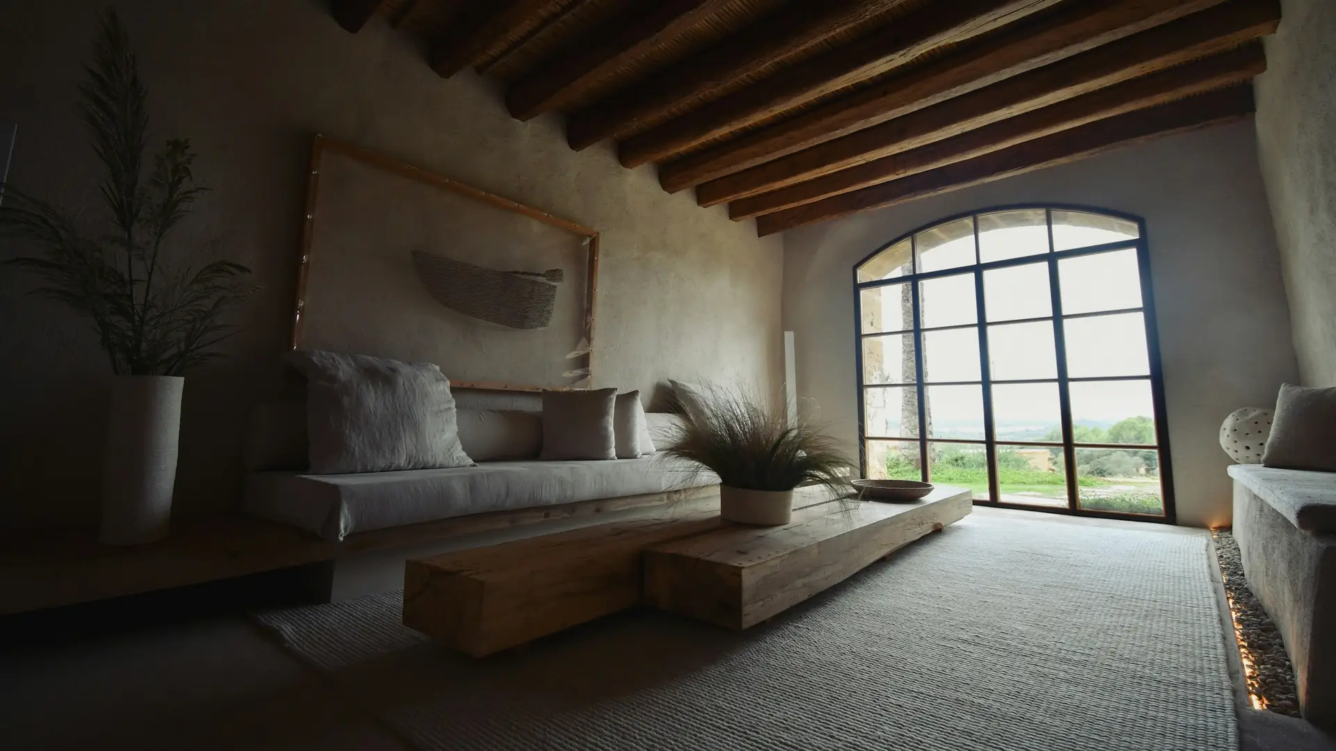 Salón reformado con vigas de madera y ventanal