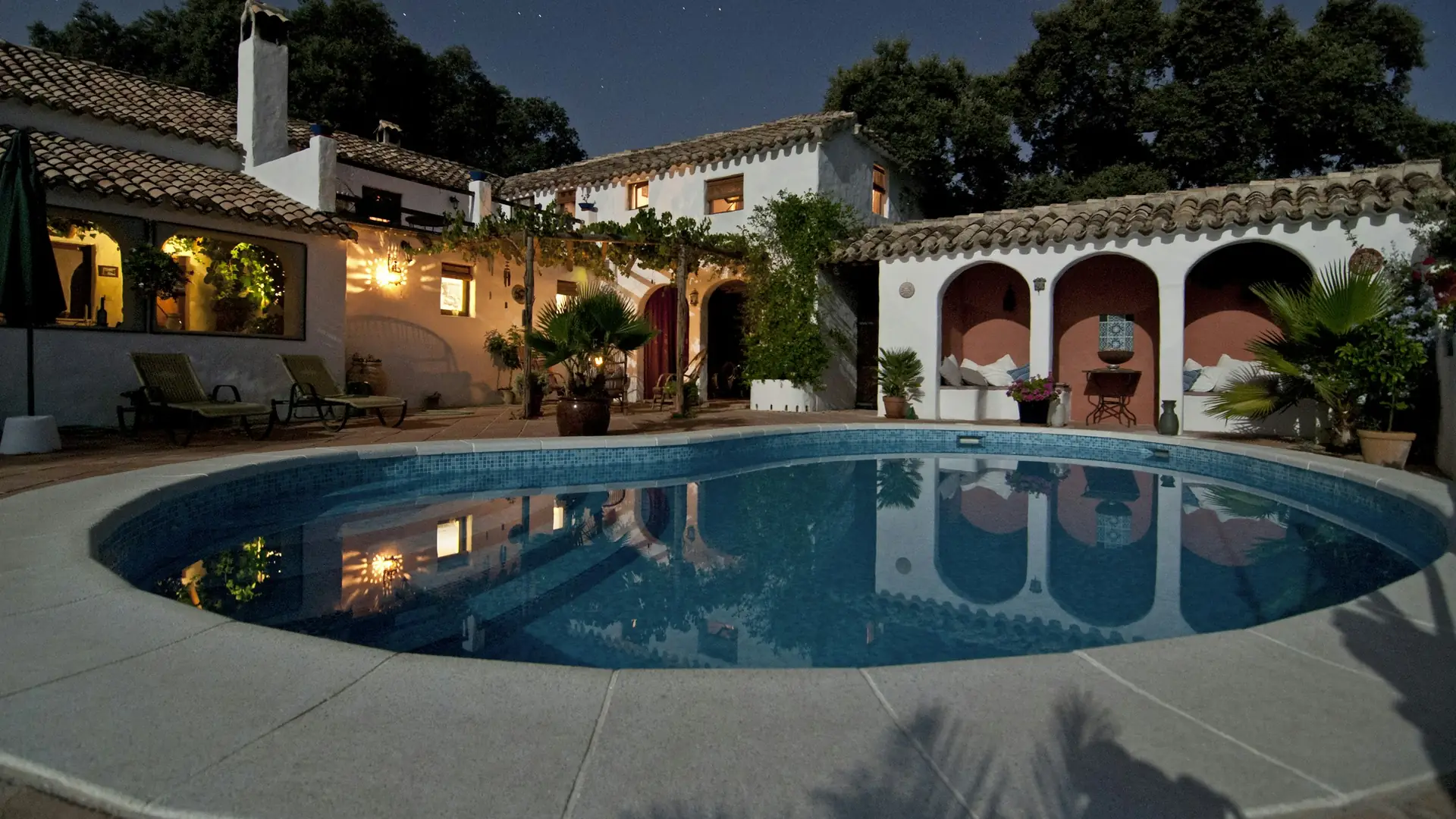 Casa mediterránea con piscina iluminada al anochecer