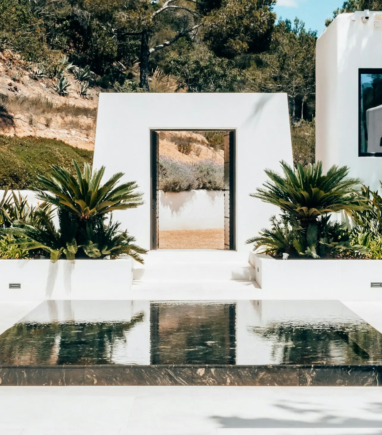 Vivienda blanca con una lámina de agua en el patio