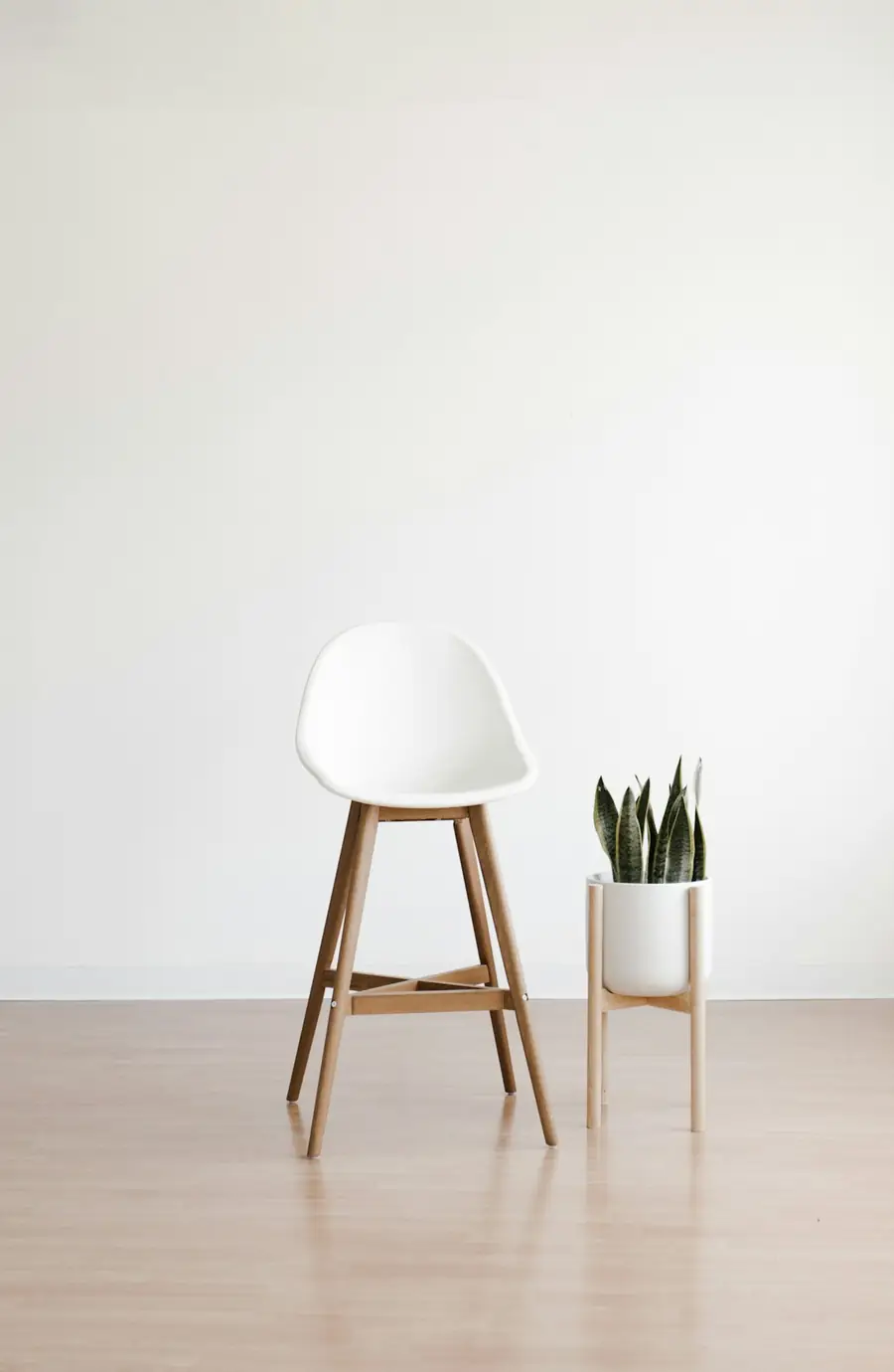 Habitación blanca recién terminada con una silla y una planta