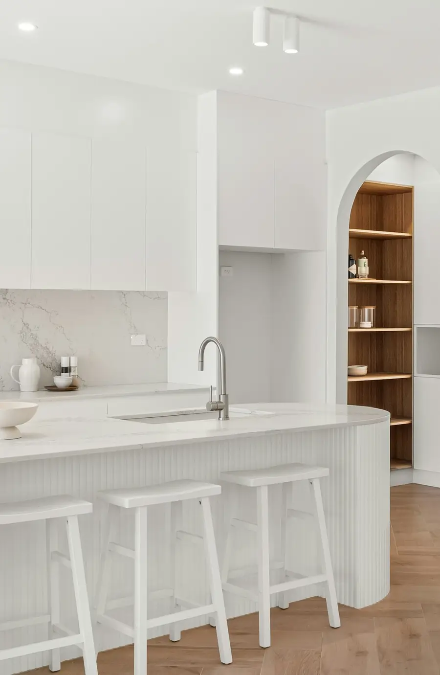 Cocina blanca reformada con barra y taburetes