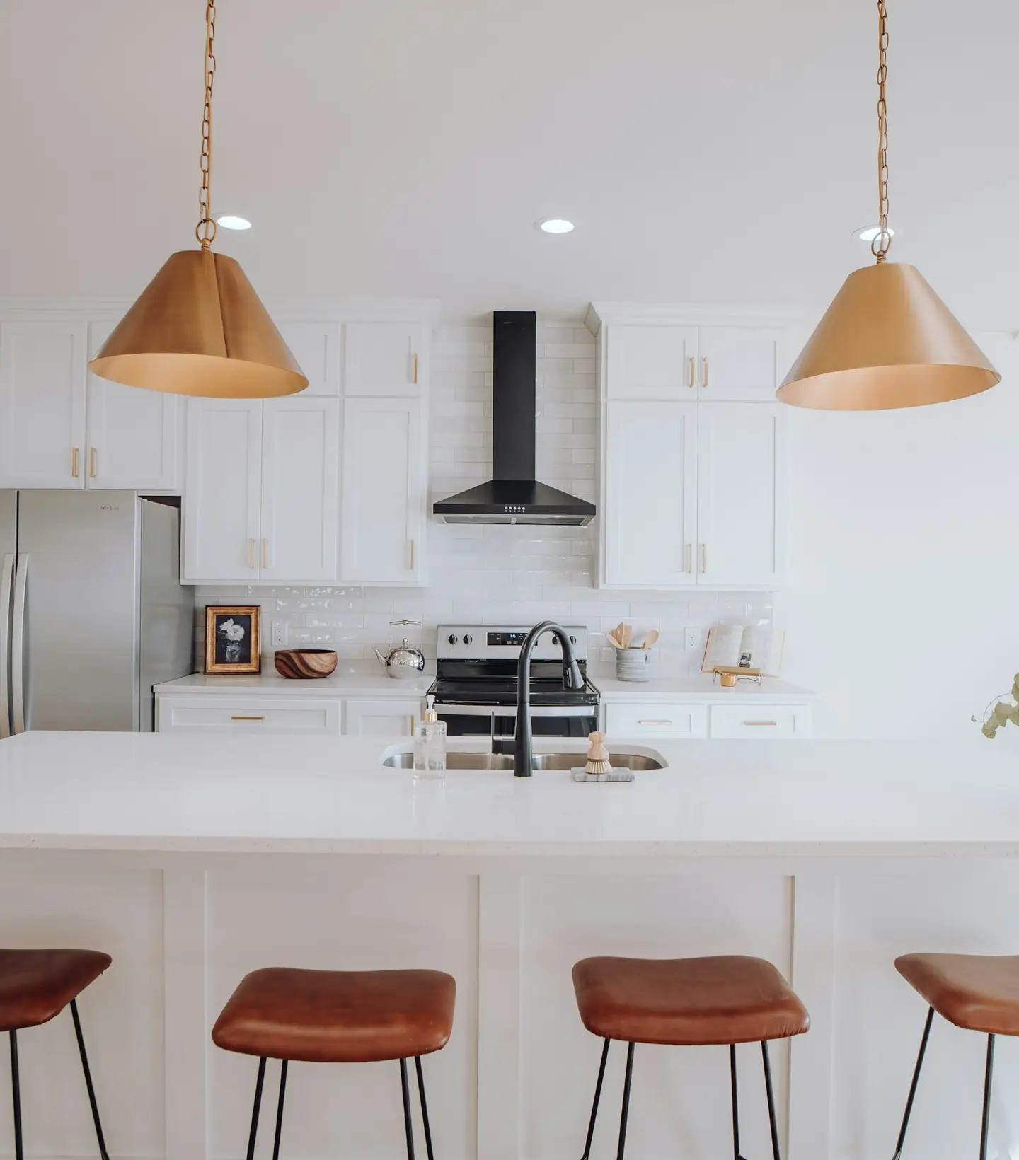 Cocina blanca con isla y lámparas de cobre